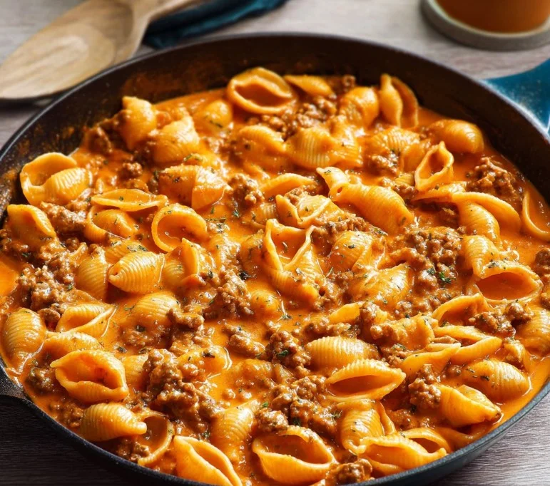 Creamy beef and shells pasta served on a plate with fresh herbs