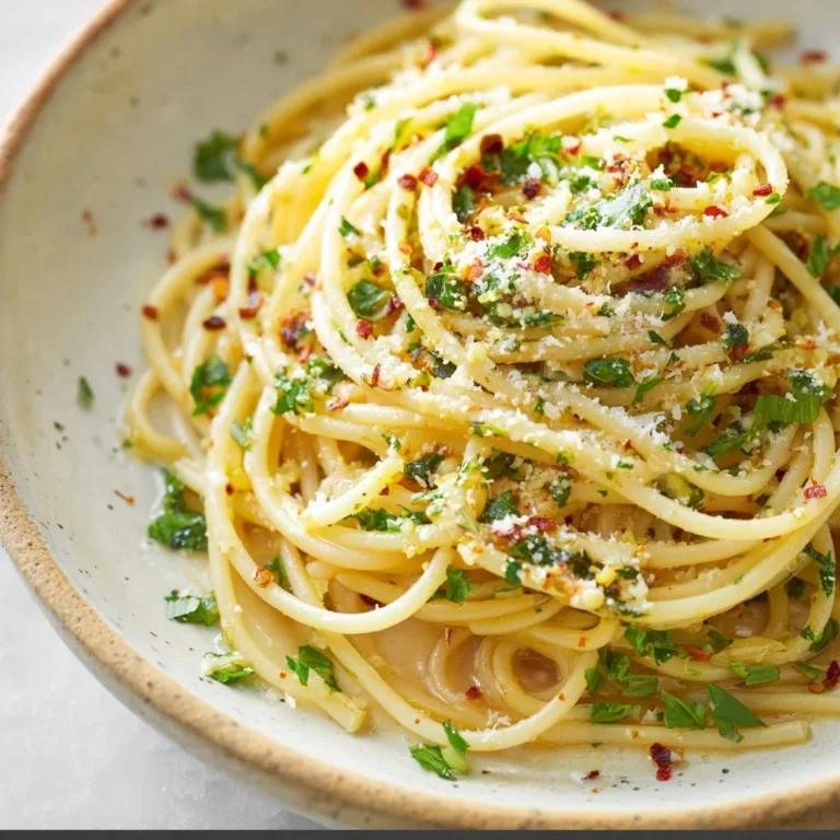 A bowl of spaghetti with garlic and olive oil, garnished with parsley.