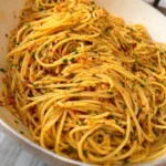 A plate of garlic butter pasta garnished with parsley and grated cheese