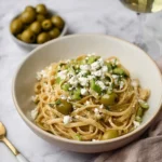 Plate of Dirty Martini Pasta garnished with olives and herbs.