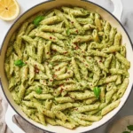 Bowl of creamy pesto ricotta pasta topped with fresh basil and grated parmesan.